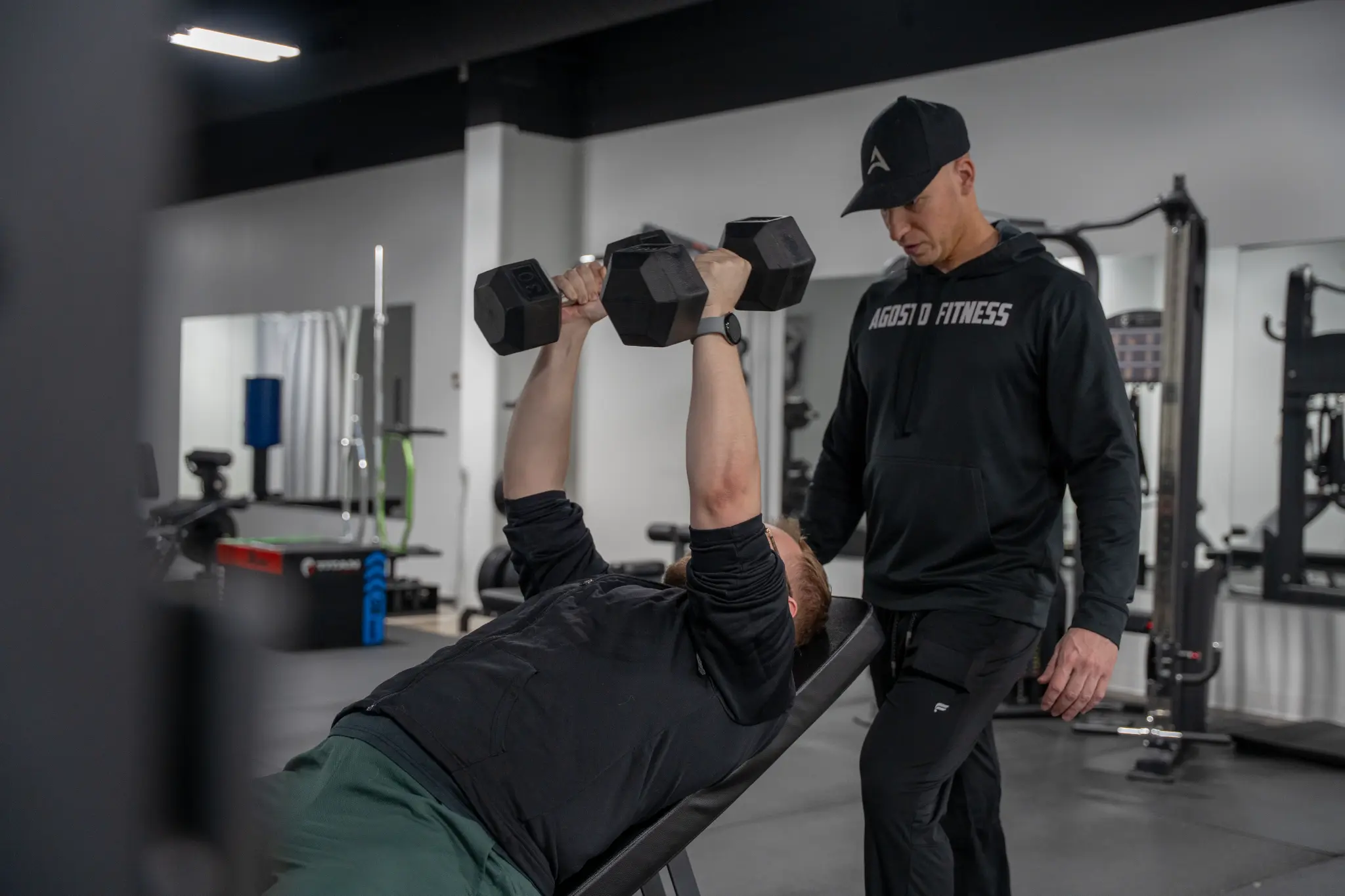 Personal trainer Garret Agosto coaching client on dumbbell bench press at Agosto Fitness Rochester NY