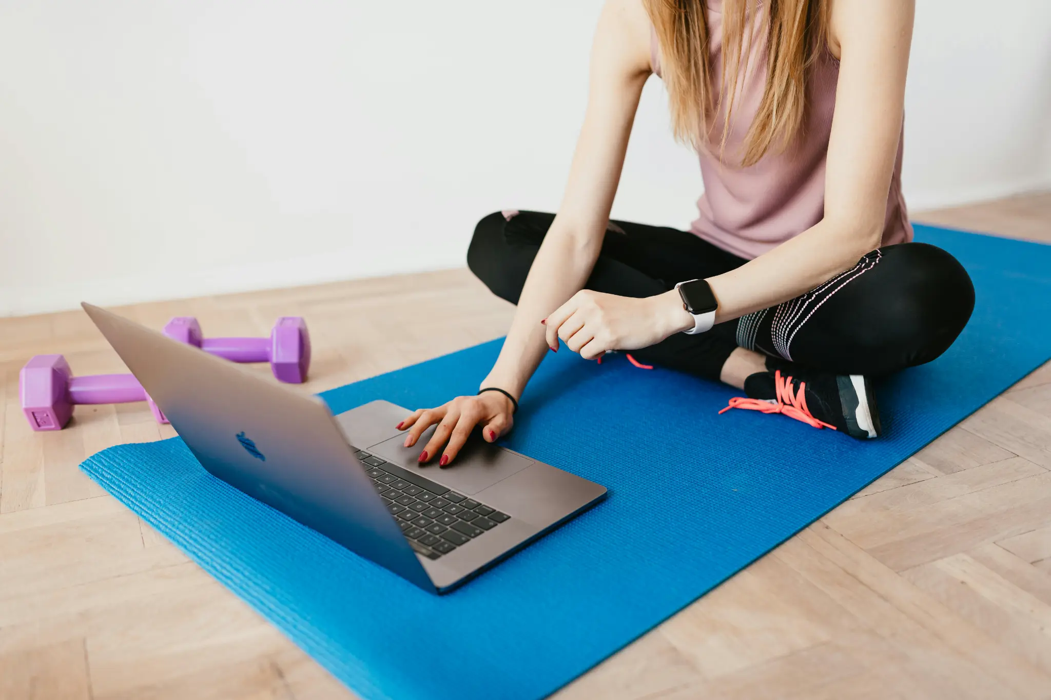 Woman on yoga mat following virtual personal training session on laptop