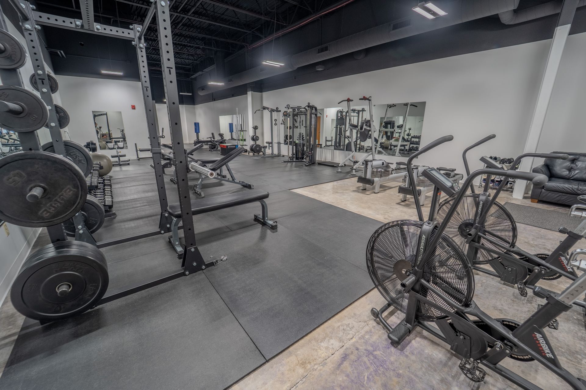 Free weight section with dumbbells and barbells at Agosto Fitness Rochester NY